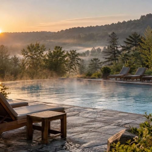Piscina aquecida de resort de campo ao amanhecer, com vapor leve e cadeiras de madeira vazias